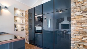 A modern kitchen with a stone accent wall, built-in appliances, and a large island. - Nice apartment in Labin with swimming pool (Labin)