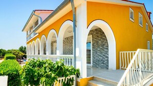 A two-story building with a yellow facade, white arches, and a red roof. - Nice apartment in Labin with swimming pool (Labin)