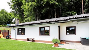 A single-story building with a tiled roof, a small porch, and a grassy yard. - modernes Ferienhaus mit Garten (Techelsberg)
