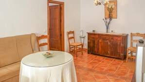 A cozy living room with a beige sofa, a round glass table with a bowl, wooden chairs, a wooden cabinet, and a TV. - 3 bedroom nice apartment in Genalguacil (Genalguacil)