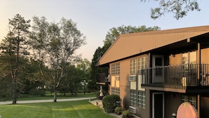 A modern two-story house with a balcony, a well-maintained lawn, and a pathway leading to the entrance.