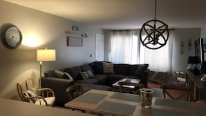A living room with a sofa, a dining table, and a TV.