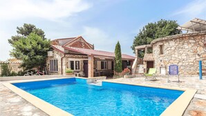 A swimming pool with a stone wall and a stone building with a tiled roof. - Stunning home in Peroj (Peroj)