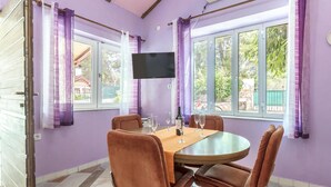 A dining area with a round table, four brown chairs, a bottle of wine, and a TV on the wall. - Stunning home in Peroj (Peroj)