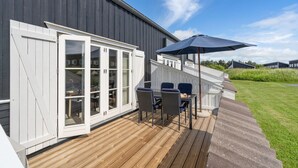 Um deck com móveis para área externa e um grande guarda-sol.