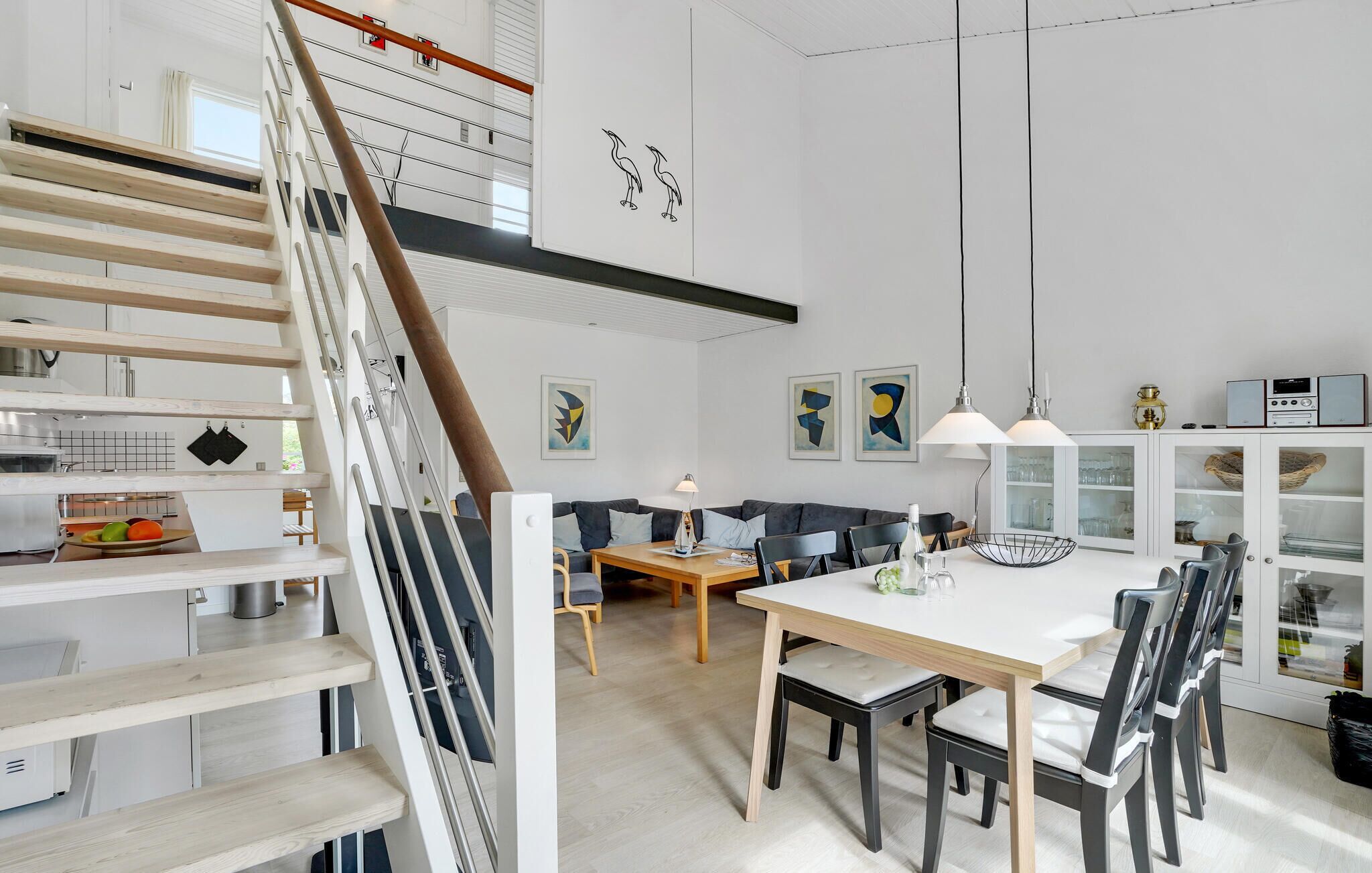 A modern interior with a staircase, dining area, and kitchen.