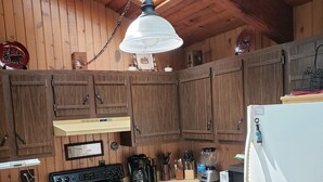 Eine Küche mit Holzausstattung, einem Herd, einer Spüle und einem Kühlschrank.
