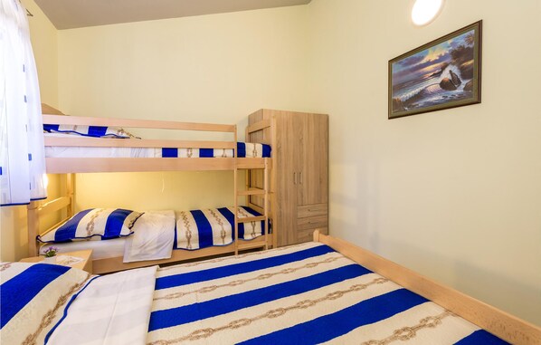 A bunk bed room with a wooden wardrobe, a painting on the wall, and a bedside table with a plant. - Amazing apartment in Kosljun with WiFi (Kosljun)
