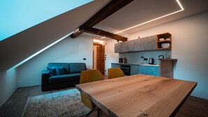 A modern loft with a dining area, a sofa, and a kitchen. - Zirm Apartment - with open air jacuzzi & infrared sauna! (Sankt Sigmund)