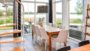 A dining area with a wooden table and chairs, large windows with a view of a lake, and a hanging light fixture. - 5 bedroom beautiful home in Karlstad (Karlstad)