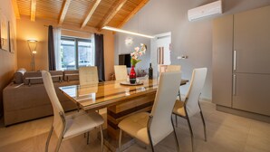 A modern kitchen with a glass dining table, white chairs, and a wooden ceiling.