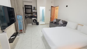 A hotel room with a bed, a TV, a washing machine, and a kitchenette. - A.1.7 (Marsa Alam)