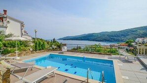A swimming pool with lounge chairs and a view of the sea and hills. - 4 bedroom beautiful home in Rabac (Rabac)