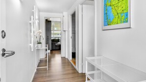 A hallway with a white bench, a map on the wall, and a door leading to a room with a desk and chair. - Gorgeous apartment in Ringkøbing (Ringkøbing)