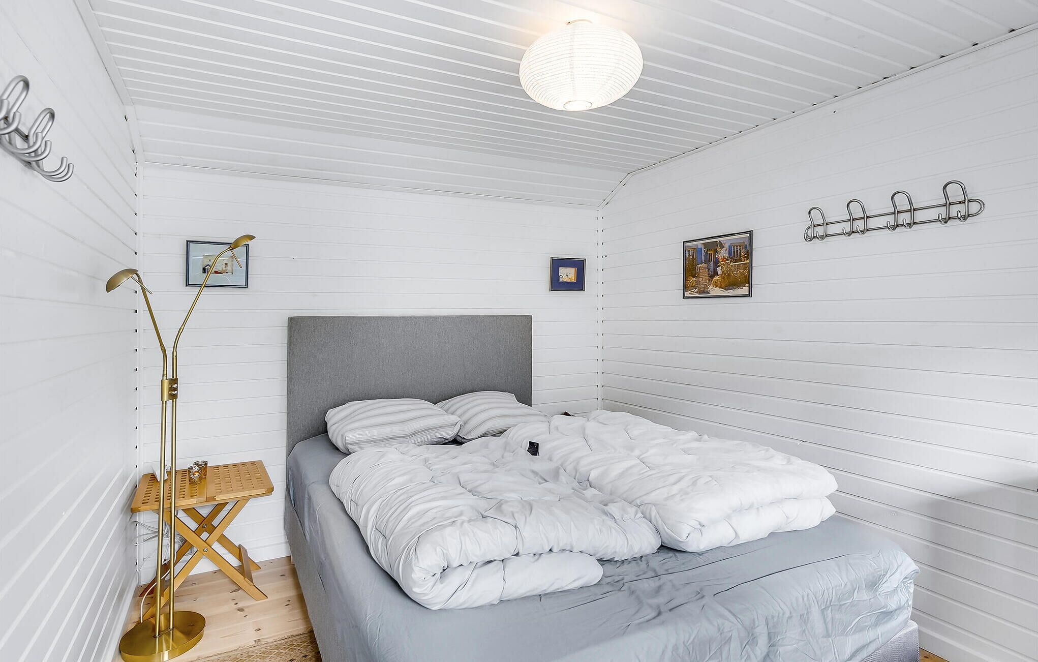 A bedroom with a bed, a floor lamp, and a wall-mounted light fixture.