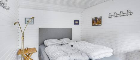 A bedroom with a bed, a floor lamp, and a wall-mounted light fixture.