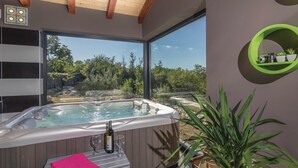 Un spa moderno con bañera de hidromasaje, ventanas amplias y vistas a un paisaje natural.