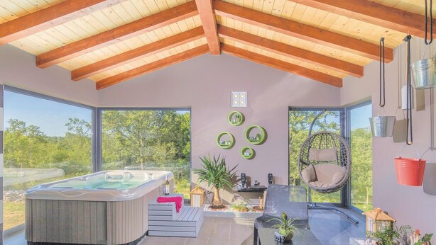 Un área de spa moderna con jacuzzi, asientos y vistas al exterior.