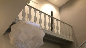 Un escalier avec une rampe blanche et un luminaire blanc, ressemblant à un nuage, placé au-dessus.