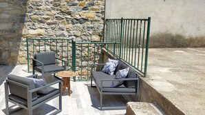 Un espace extérieur aménagé avec deux canapés, une petite table ronde et un mur en pierre en arrière-plan.