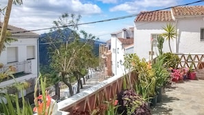 A residential street with white houses, a metal fence, and potted plants. - Nice apartment in Genalguacil (Genalguacil)