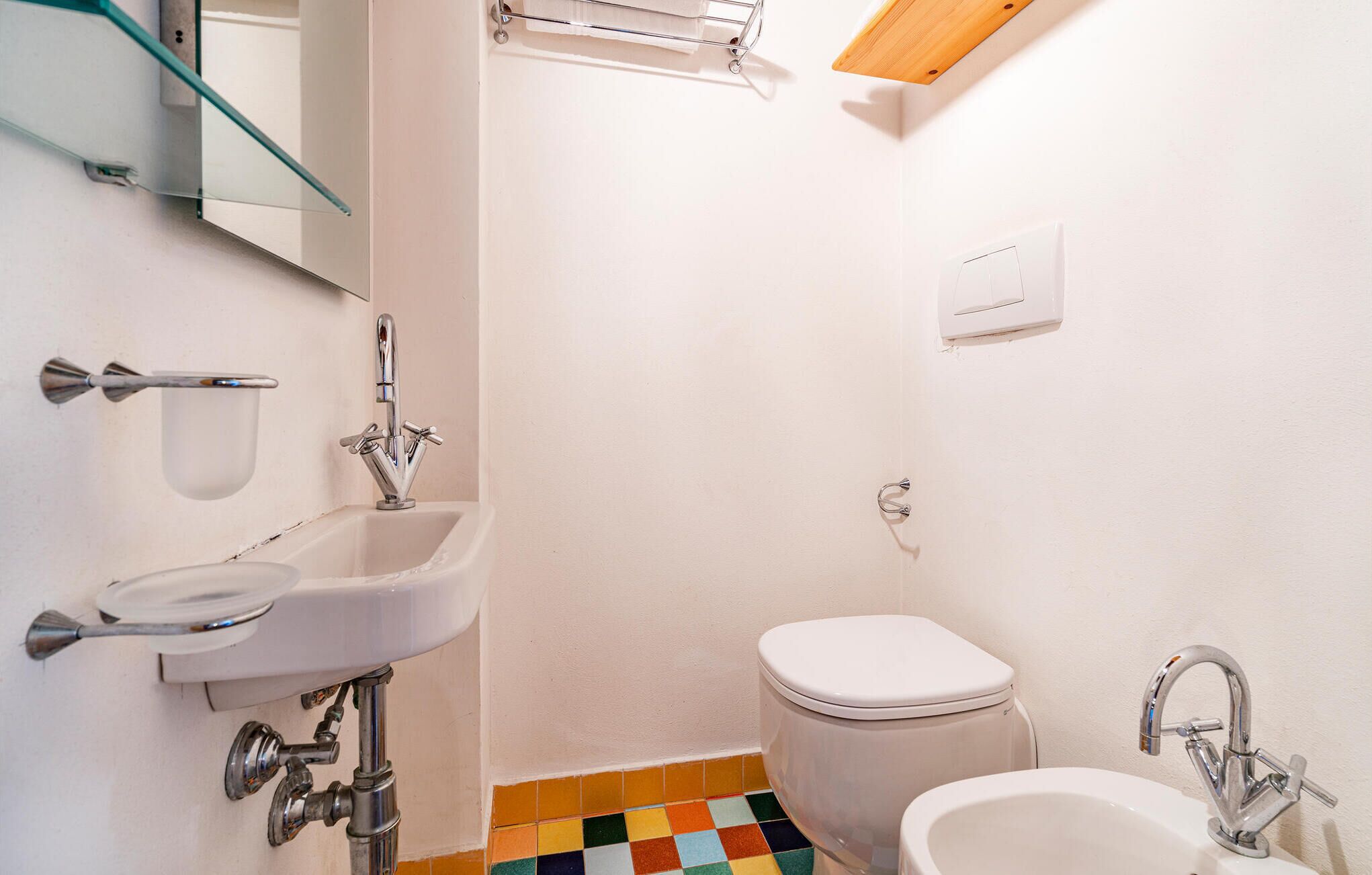 Een kleine badkamer met een witte wasbak, toilet en een douchetoilet.