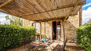 A stone building with a thatched roof patio, outdoor seating, and a stone wall. - Nice home in Montaione (Montaione)