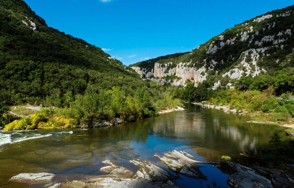 A river flowing through a valley with rocky cliffs and dense greenery.