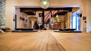 Ein Holztisch mit vier Weingläsern und Tellern, in einem rustikalen Innenraum mit freiliegenden Balken und einer Steinwand.