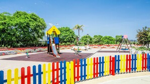 Un'area giochi con attrezzature colorate e una recinzione decorativa.