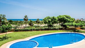 Una piscina a forma curva, circondata da un prato curato e alberi.