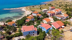 An aerial view of a coastal village with houses featuring red-tiled roofs, surrounded by greenery and a clear blue sea. - Amazing apartment in Kosljun with WiFi (Kosljun)