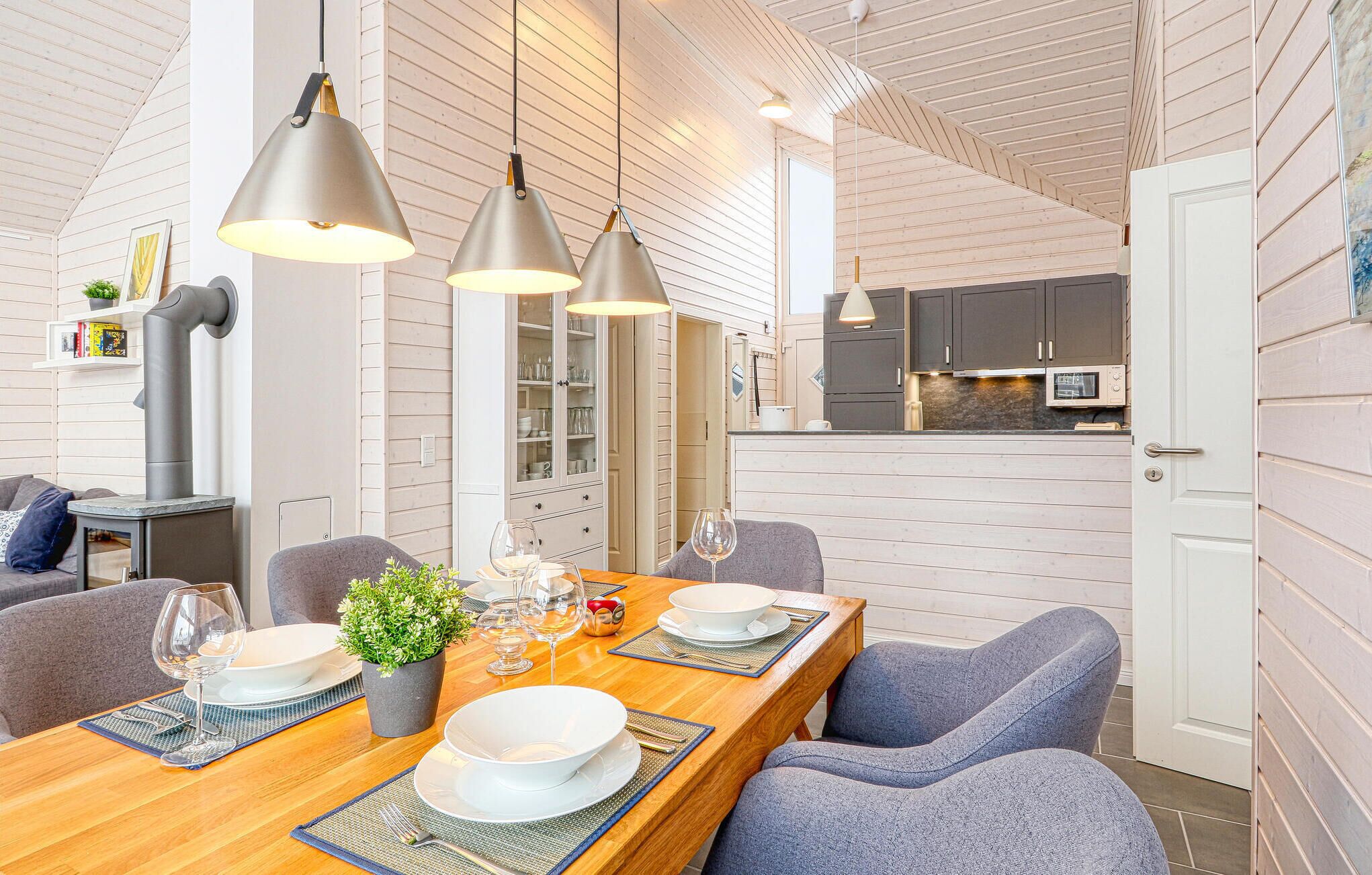 Une cuisine moderne avec des meubles blancs, un micro-ondes encastré et un coin repas doté d’une table en bois, mise pour quatre personnes.