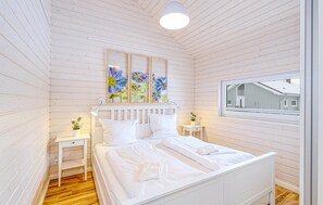 A bedroom with a wooden slat ceiling, a bed with white bedding, two bedside tables with lamps, and a window with a view of a house. - Lovely home in Krems II/Warderbrück with sauna (Krems II/Warderbrück)