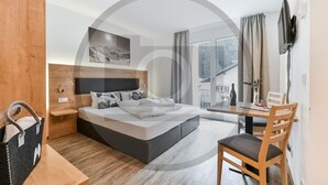 A modern hotel room with a large bed, a desk, and a view of the outdoors. - attraktive Ferienwohnung (Klösterle)