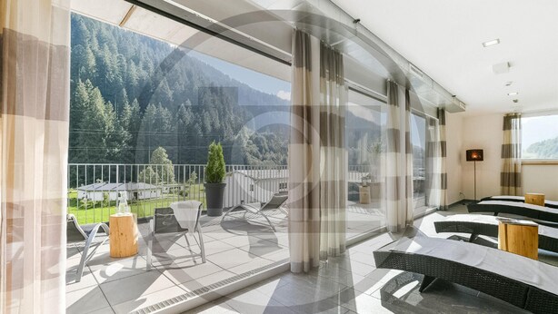 A modern hotel room with a large balcony, a view of a forested mountain, and a dining area with outdoor furniture. - attraktive Ferienwohnung (Klösterle)