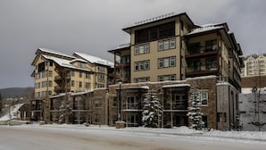 A multi-story hotel with a stone facade, multiple balconies, and snow-covered surroundings. - Location and Comfort - One Bedroom Ski In / Ski out, Hot Tub and Fire Pit (Winter Park)