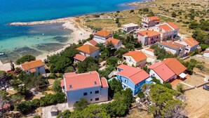 An aerial view of a coastal village with houses featuring red-tiled roofs, surrounded by greenery and a clear blue sea. - 1 bedroom lovely apartment in Kosljun (Kosljun)