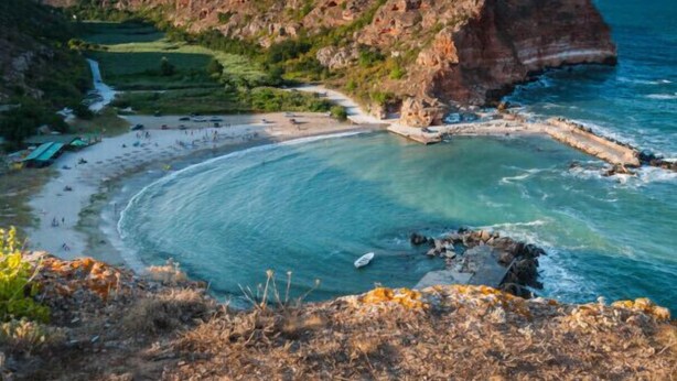 Paisaje costero con playa, acantilados y un río.