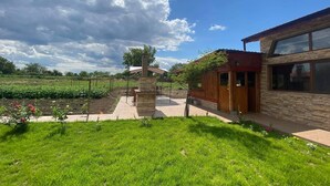 Una casa moderna con chimenea de piedra, terraza de madera y un jardín bien cuidado.