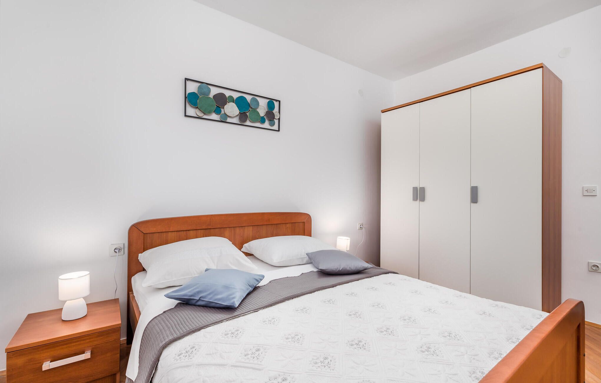 A bedroom with a bed, bedside tables, a night lamp, a wardrobe, and a wall art piece.