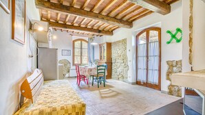 A cozy room with a wooden ceiling, stone walls, a dining area with a table and chairs, and a bed with a patterned mattress. - 2 bedroom cozy home in Montaione (Montaione)