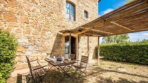 A stone building with a wooden pergola, outdoor seating, and a view of the surrounding greenery. - 2 bedroom cozy home in Montaione (Montaione)