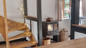 A rustic interior with exposed wooden beams, a traditional wood-burning stove, and a wooden staircase. - 2 bedroom nice home in Harpelunde (Harpelunde)