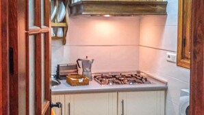 Une cuisine avec des meubles blancs, une cuisinière à gaz et un évier.