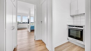 Eine moderne Küche mit weißen Schränken, einem Einbauofen und Blick auf einen Balkon.