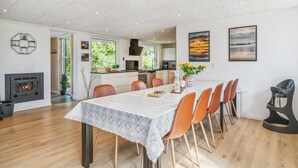 Una cocina moderna con armarios blancos, horno empotrado y comedor con mesa para seis personas.