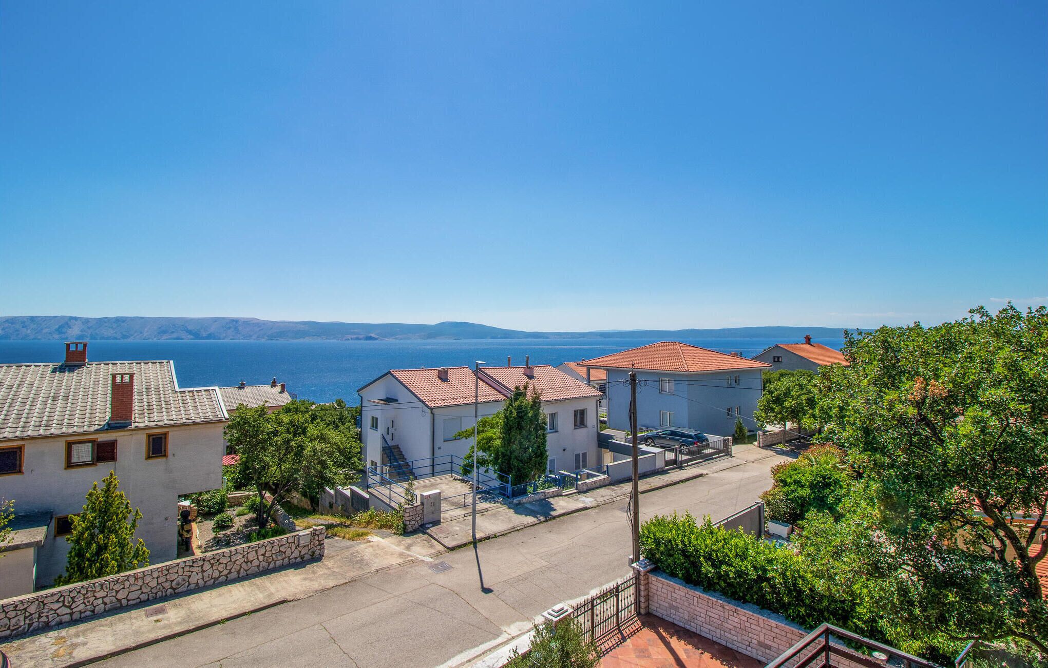 A coastal residential area with houses, a clear blue sky, and a view of the sea.