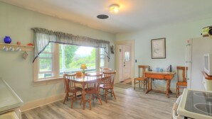 Un coin repas avec une table et des chaises en bois, une fenêtre avec des rideaux, une carte accrochée au mur et un réfrigérateur.