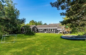 Enjoy a home with a two-story house, lawn, and trees, featuring a playhouse, trampoline, and soccer goal.
